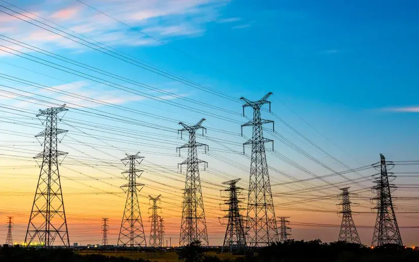 Hochspannungsleitungen und Strommast der Energieübertragung bei Sonnenuntergang
