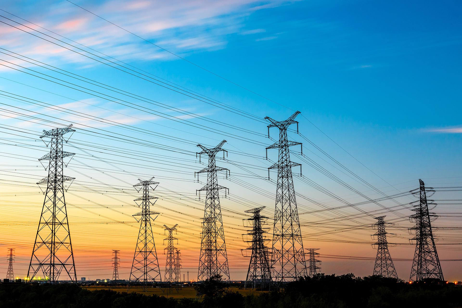 Hochspannungsleitungen und Strommast der Energieübertragung bei Sonnenuntergang