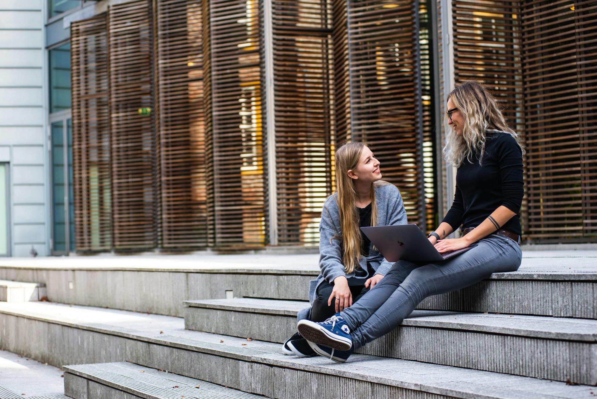 Zwei Frauen sitzen auf der Treppe und unterhalten sich